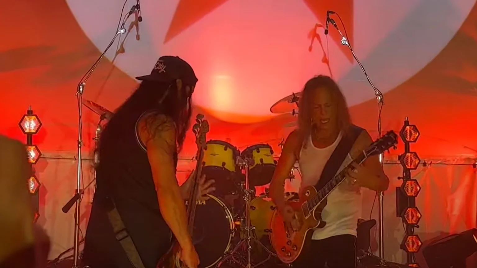Rob Trujillo and Kirk Hammett playing their guitars on stage.