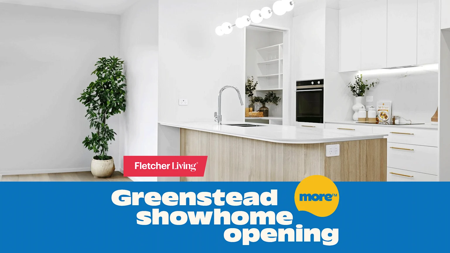 A modern white and wood kitchen interior with a plant and an island, featuring banners that announce "Fletcher Living Greenstead showhome opening."