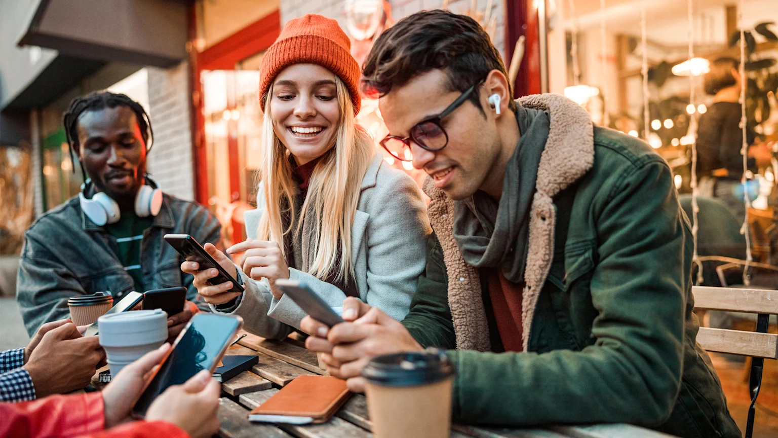 Three friends using phones at outdoor café