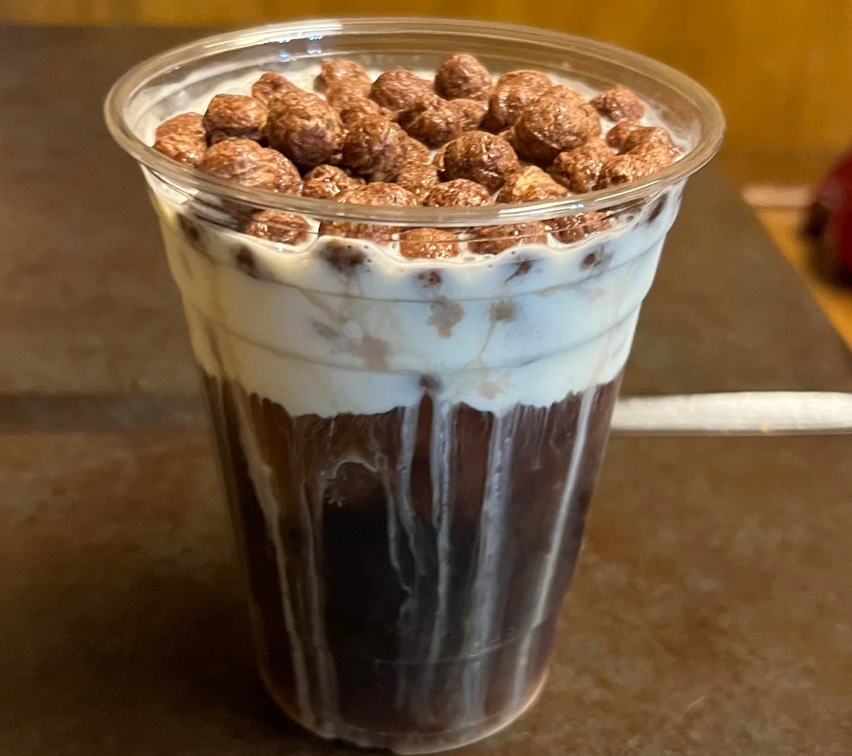 Cup of cold brew coffee topped with cream cheese foam and cocoa puffs.