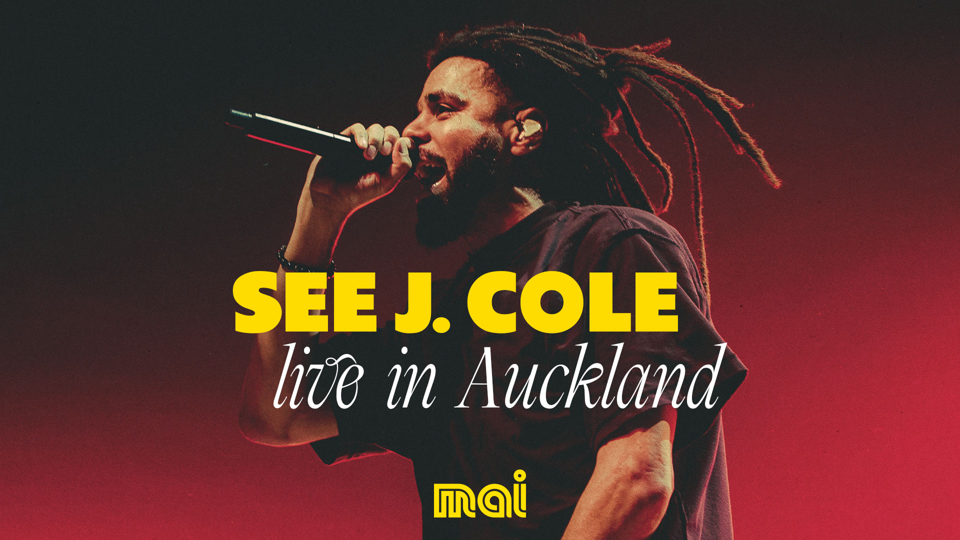 Rapper J. Cole performs live on stage, holding a microphone, with text "SEE J. COLE live in Auckland" and a "mai" logo overlay.