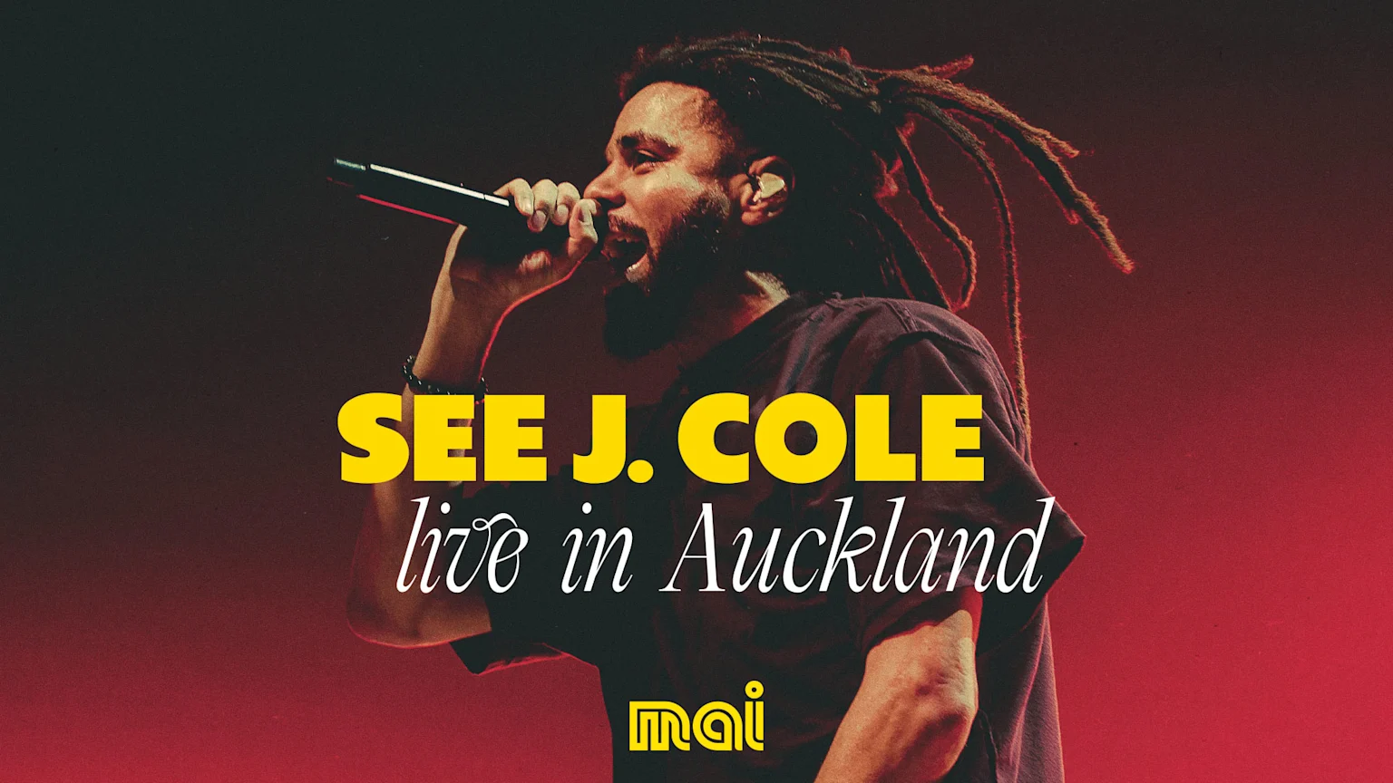 Rapper J. Cole performs live on stage, holding a microphone, with text "SEE J. COLE live in Auckland" and a "mai" logo overlay.