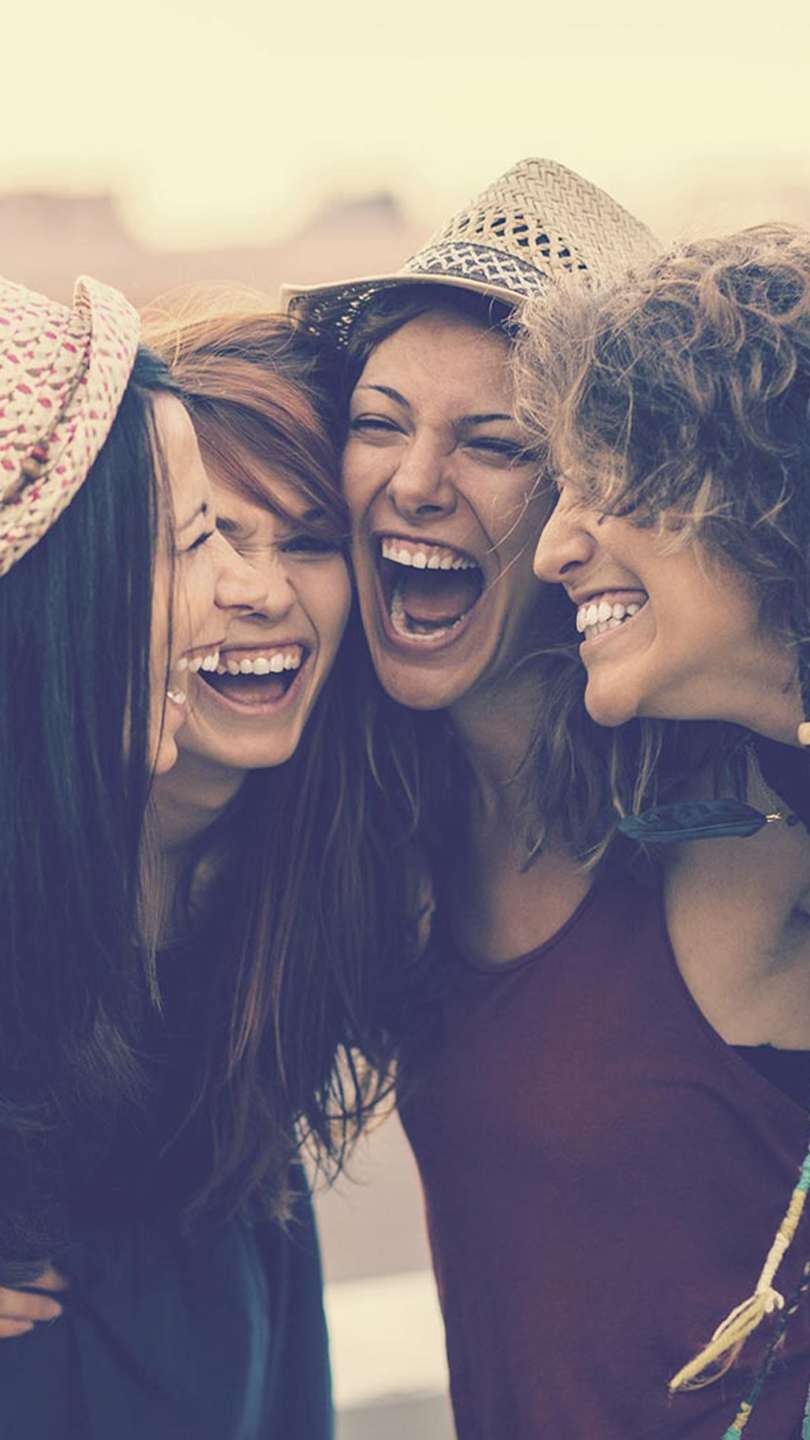 Four friends laughing together outdoors
