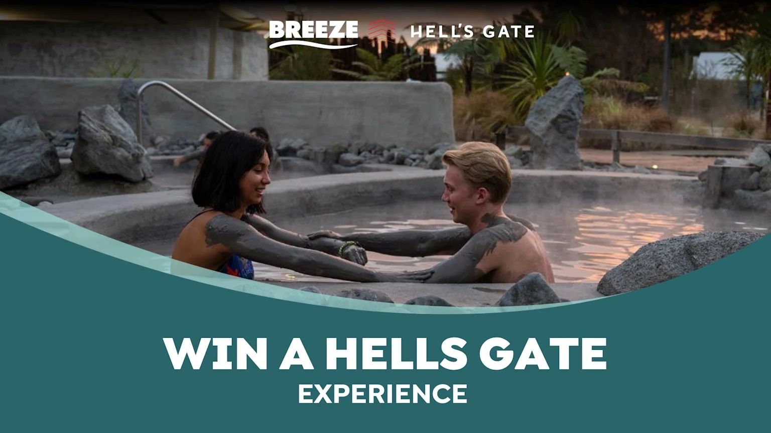Two smiling people covered in mud relax in a steamy outdoor thermal pool, surrounded by rocks and plants, with 'Breeze', 'Hell's Gate' logos, and 'Win a Hells Gate Experience' text.