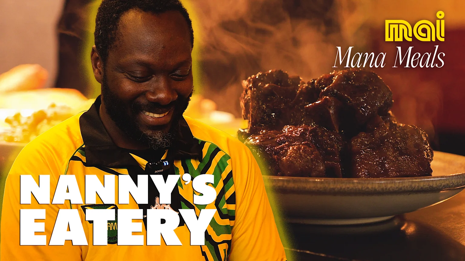 A smiling African American man in a yellow and green striped shirt is next to a steaming bowl of dark food, with "Nanny's Eatery" and "mai Mana Meals" text overlays.