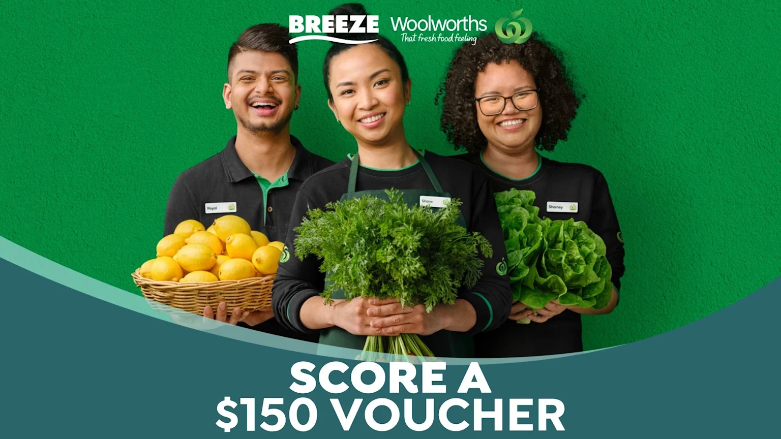 Three happy Woolworths employees in green uniforms, with arms outstretched, stand in a fresh produce aisle, surrounded by vegetables, with text "WIN A $150 VOUCHER" prominently displayed.