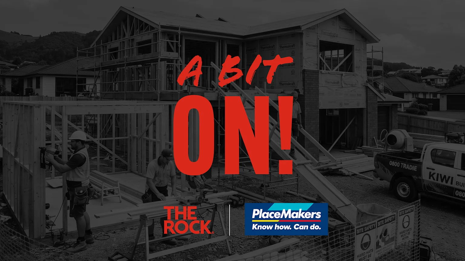Desaturated image of a house under construction with workers and a truck, overlaid with red text "A BIT ON! THE ROCK" and the blue "PlaceMakers" logo.