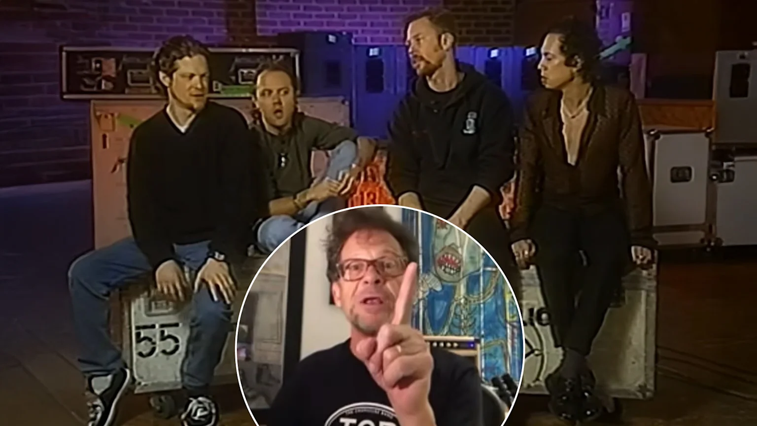 Four men sit on grey road cases in a room, with a circular inset showing a man in glasses pointing his right index finger upwards.