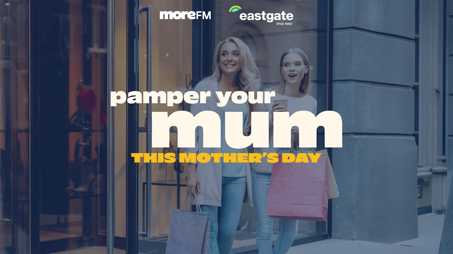 Two smiling women carrying shopping bags walk out of a store, with text "pamper your mum THIS MOTHER'S DAY" and "moreFM eastgate" logos overlaid.
