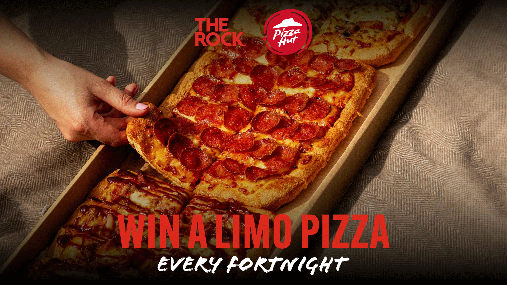 A hand reaches for a slice of a long, rectangular pepperoni pizza, also known as a "Limo Pizza," from a box, with Pizza Hut logos and "Win a Limo Pizza Every Fortnight" text.