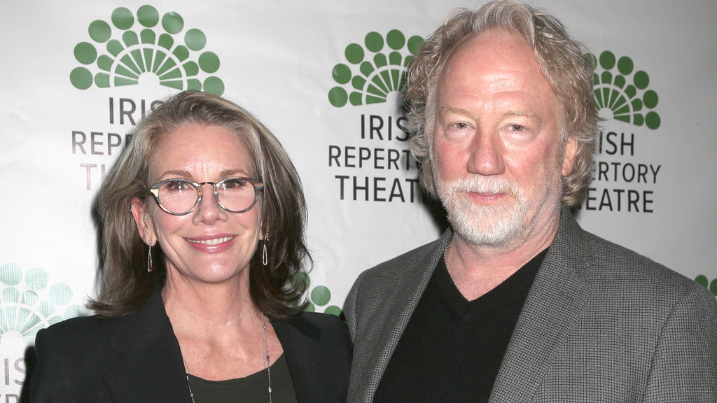 Actress Melissa Gilbert, wearing glasses and a black blazer, smiles next to actor Timothy Busfield, who has a beard and is in a gray blazer, against an Irish Repertory Theatre backdrop.