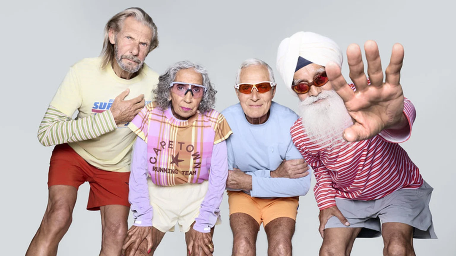Four older adults in colorful athletic wear and sports glasses strike poses; one woman wears a "Cape Town Running Team" top, and a man with a turban and white beard extends his hand.