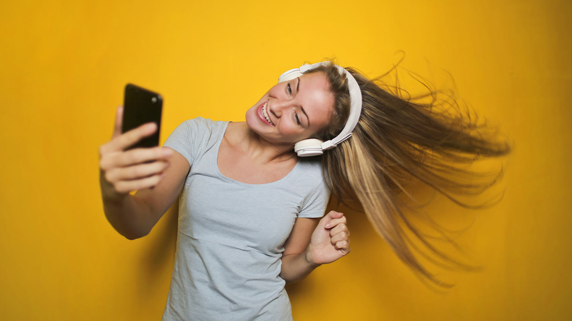 Person dancing with headphones against yellow background