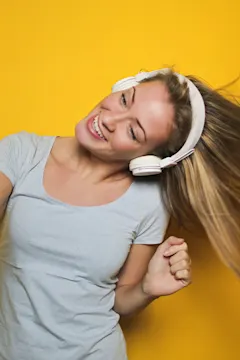 Person dancing with headphones against yellow background