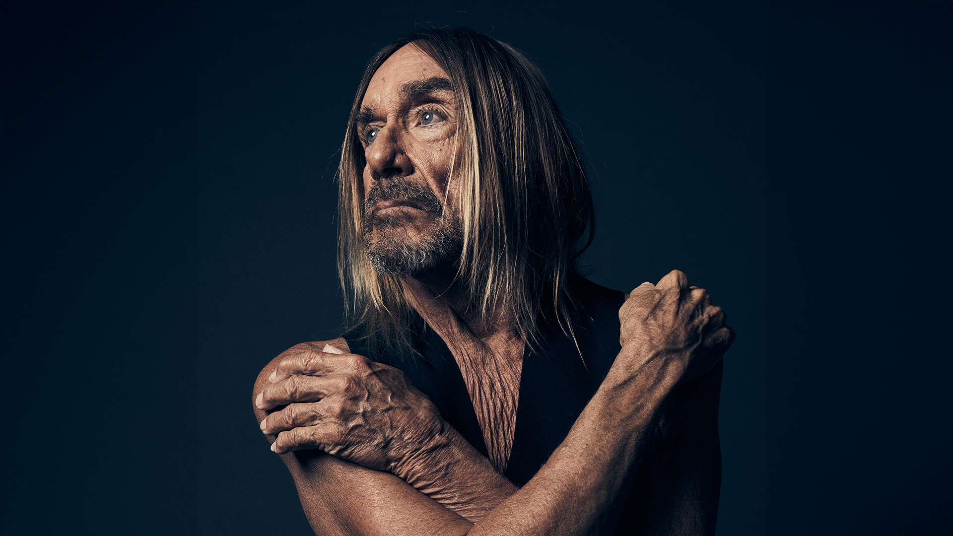 Musician Iggy Pop crossing his arms, staring to the left