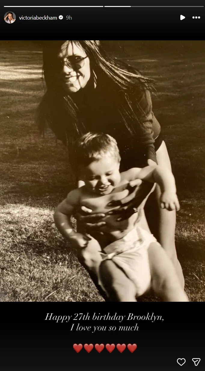Sepia-toned photo of Victoria Beckham smiling and holding a baby on a grassy background, with text "Happy 27th birthday Brooklyn, I love you so much."