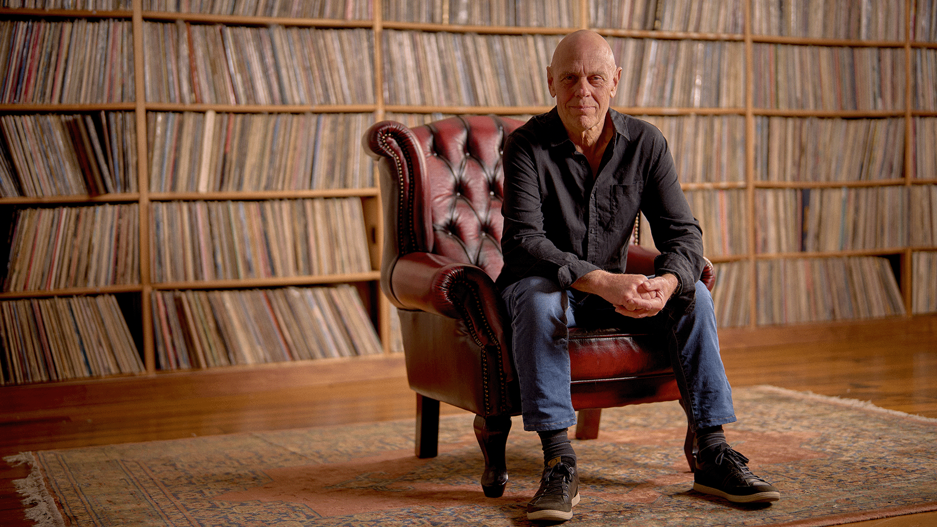 John Markby sits in a leather chair in front of record collection