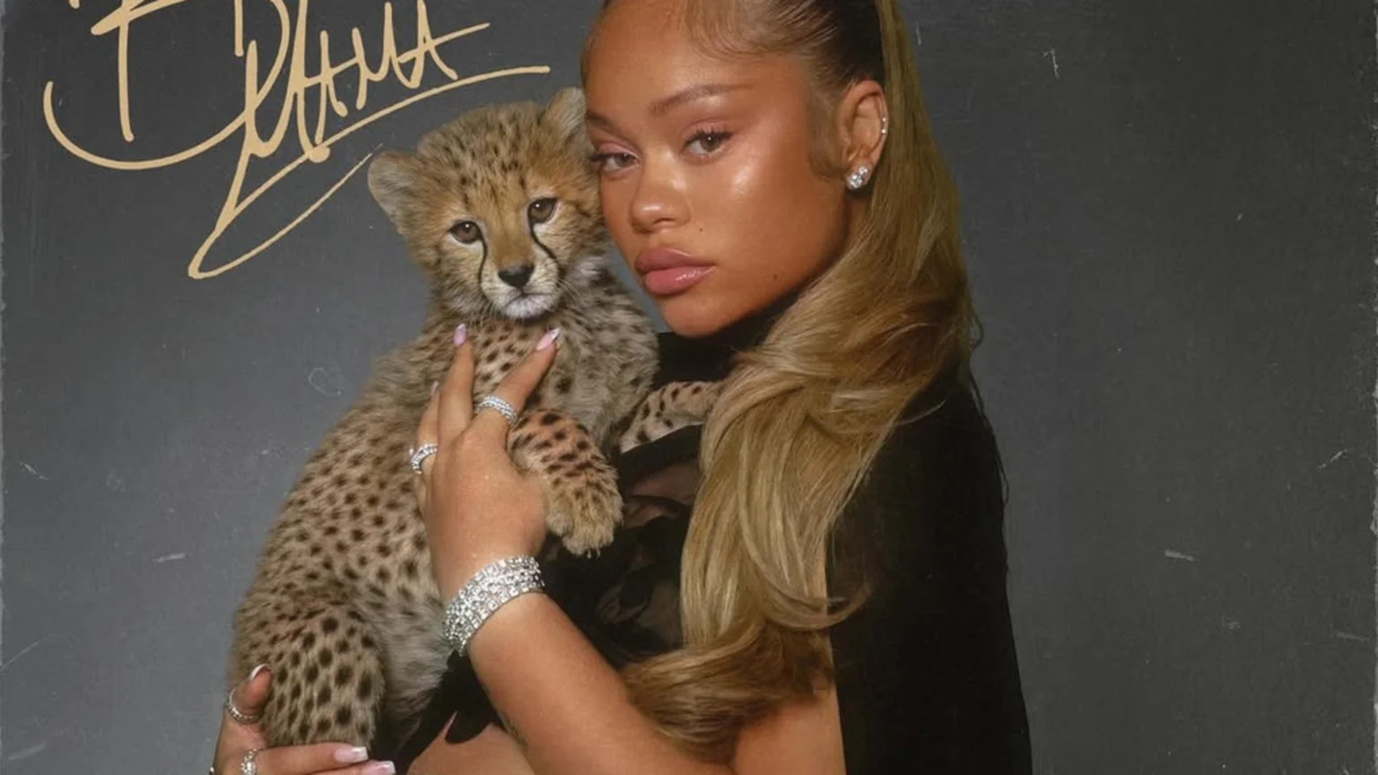 A woman with long blonde hair holds a small cheetah cub against a dark background, with the cursive text "Big Mama" visible at the top left.