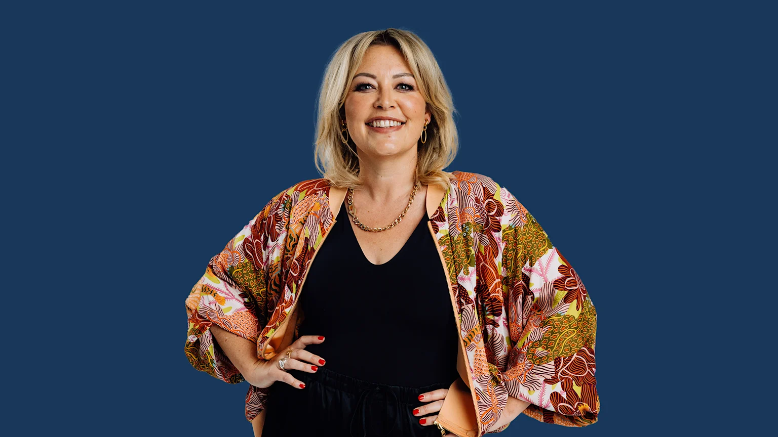 Sarah Gandy stands and smiles with a blue background