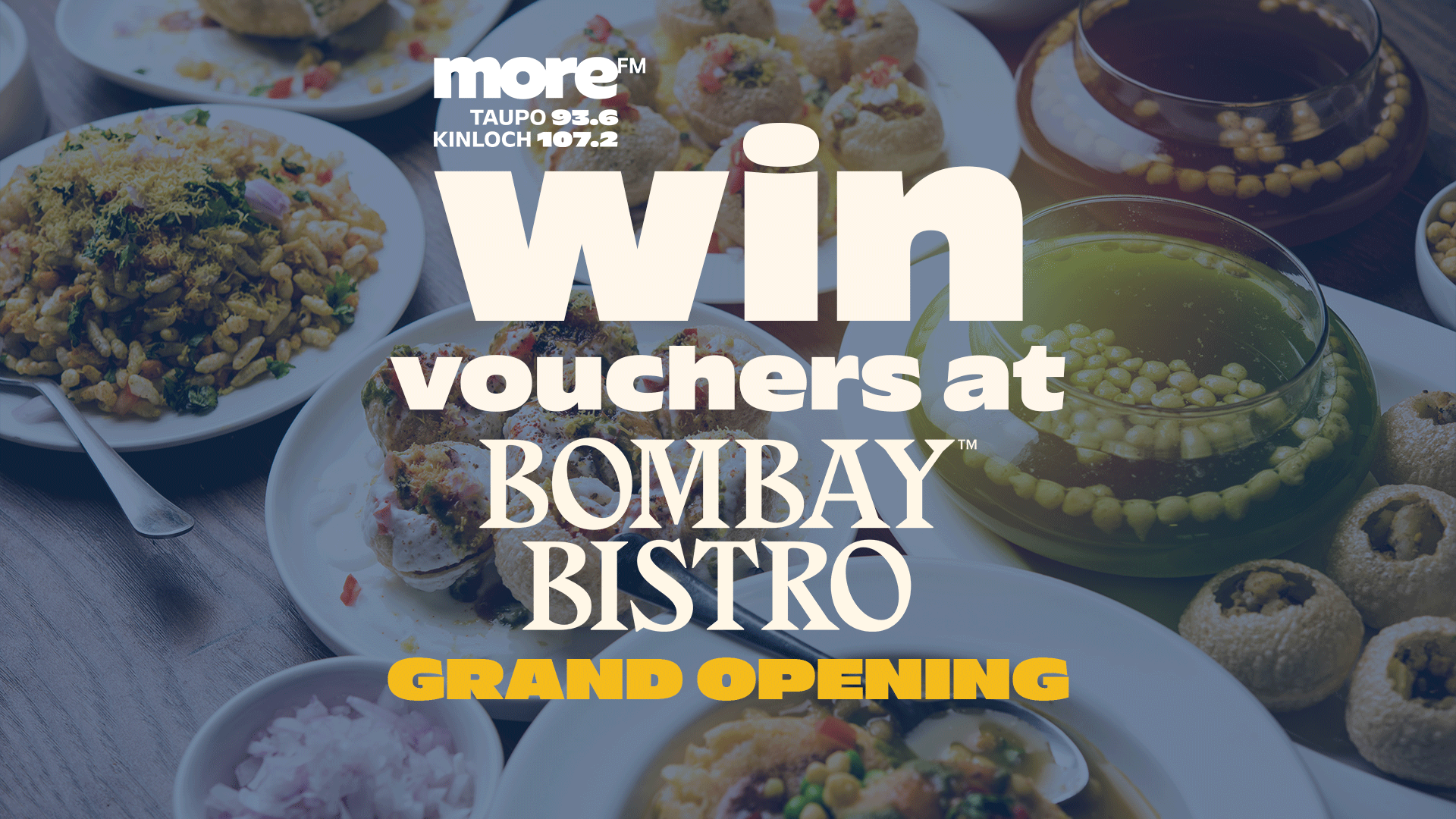 A table laden with various Indian dishes, featuring text "Win vouchers at Bombay Bistro Grand Opening" and More FM branding.