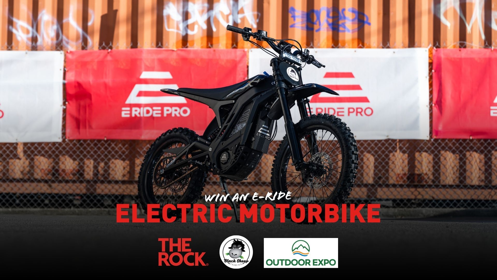 A black electric motorbike is centered against red and white "E RIDE PRO" banners, with text overlay "WIN AN E-RIDE ELECTRIC MOTORBIKE" and sponsor logos.