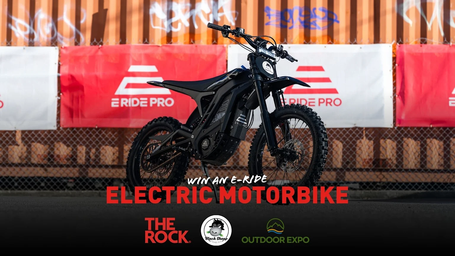 A black electric motorbike is centered against red and white "E RIDE PRO" banners, with text overlay "WIN AN E-RIDE ELECTRIC MOTORBIKE" and sponsor logos.