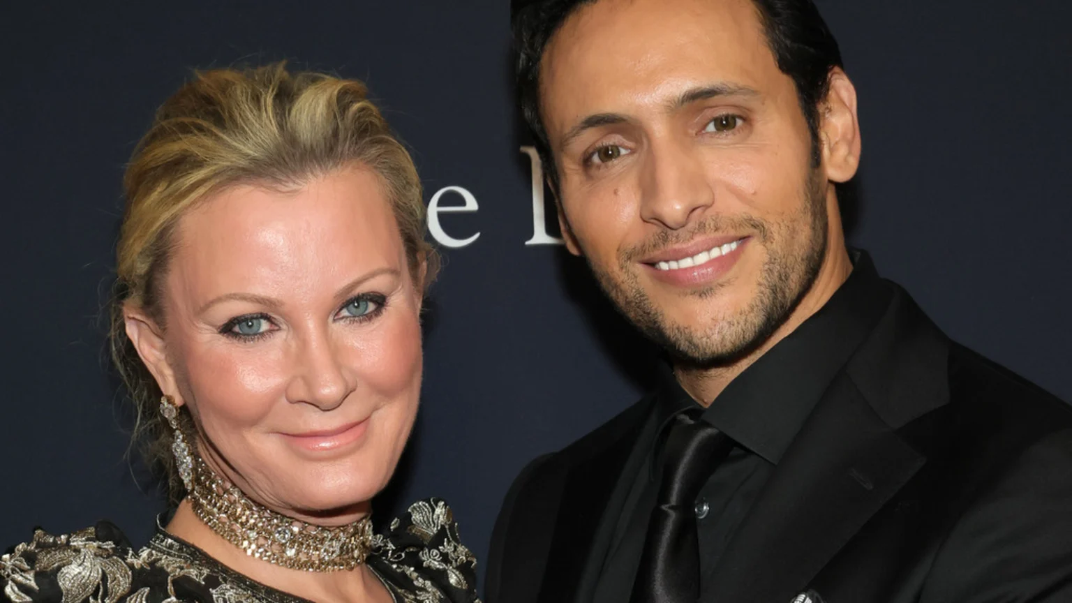 Sandra Lee, a blonde woman in an ornate top, smiles next to Ben Youcef, a dark-haired man with a beard in a black suit, as they both look at the camera.