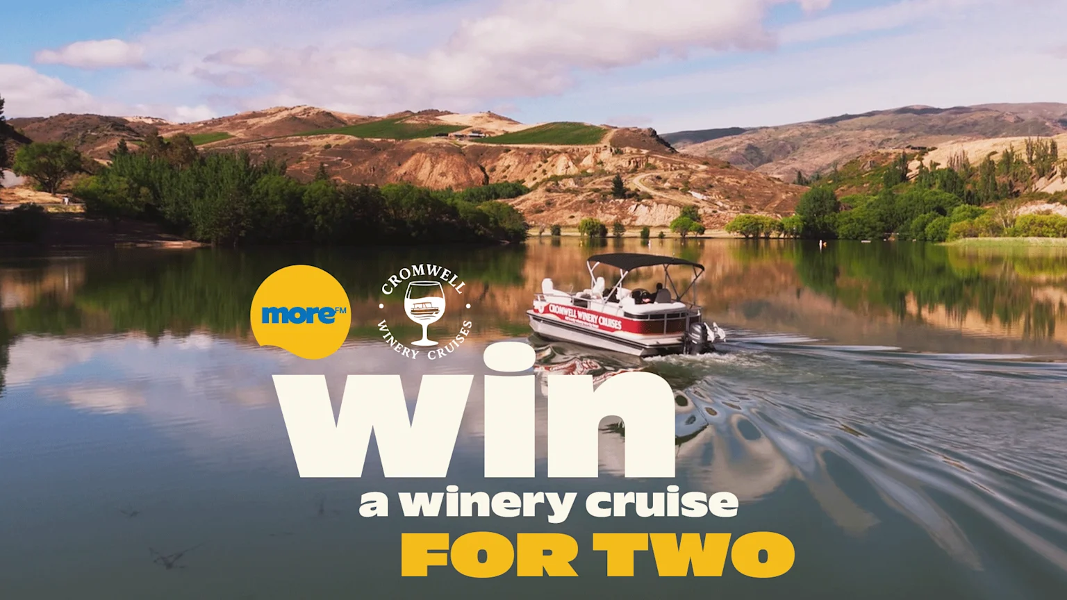 A boat cruises on a lake surrounded by hills and vineyards, with overlaid text "Win a winery cruise FOR TWO" and logos for More FM and Cromwell Winery Cruises.