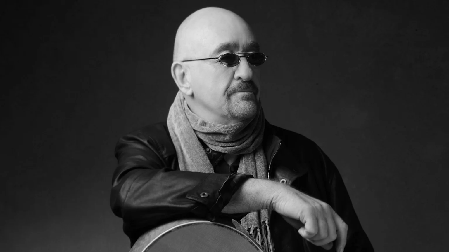 black and white photo of Dave Mason with his guitar looking off to the right