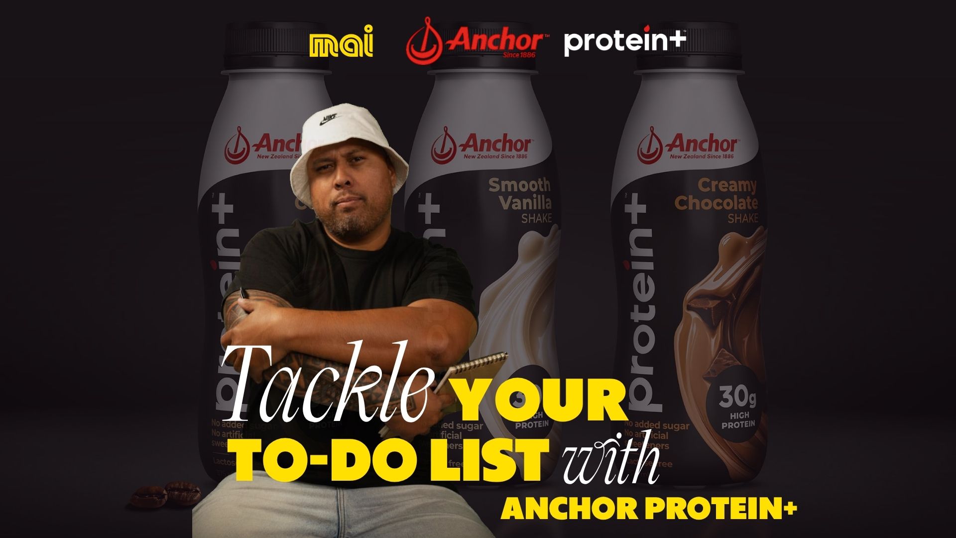 A man in a bucket hat with a notepad sits in front of three Anchor Protein+ shake bottles (vanilla, chocolate) with logos for Mai and Anchor, and text "Tackle YOUR TO-DO LIST with ANCHOR PROTEIN+".