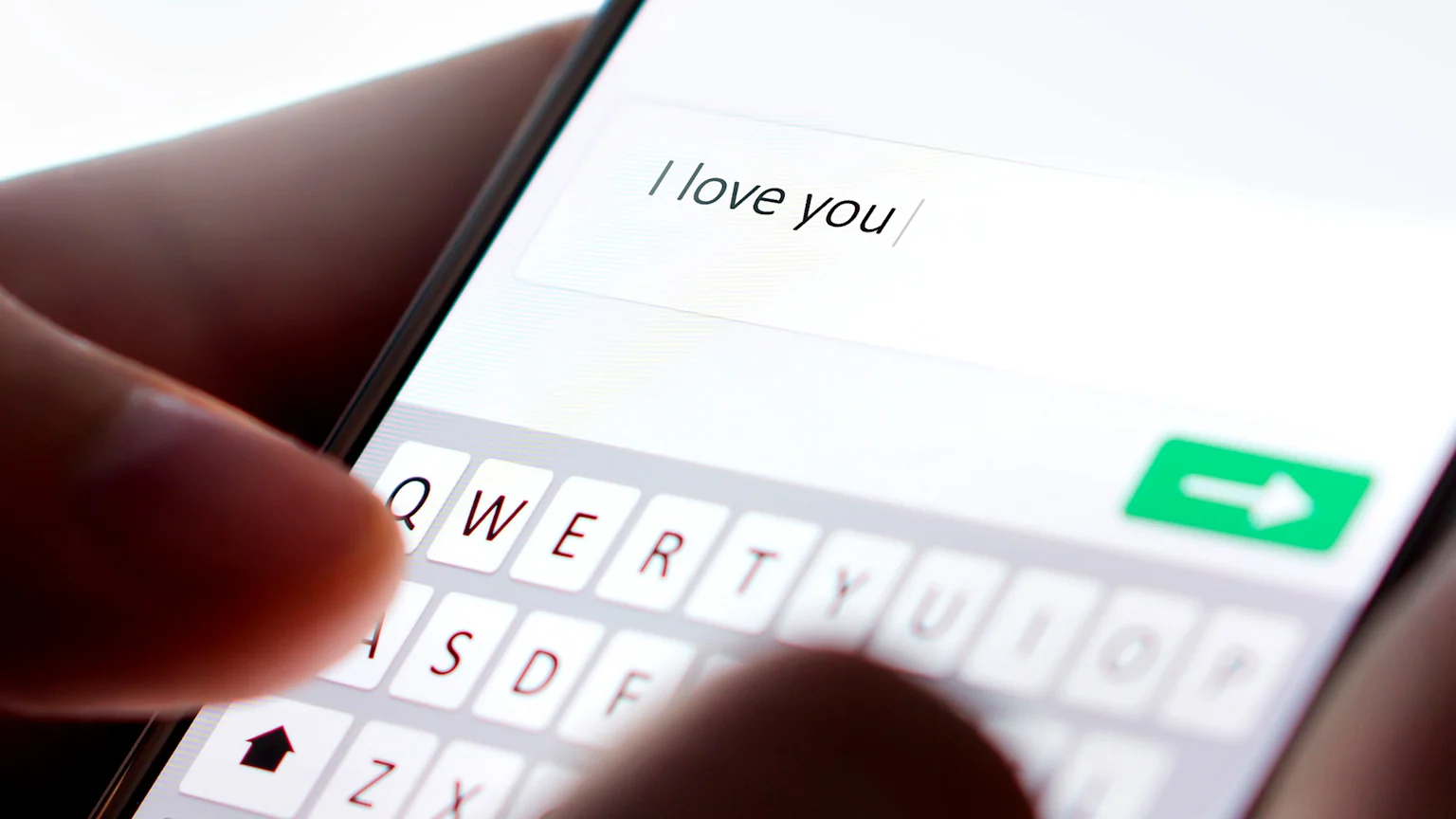 Female hands typing "I love you" on a phone.