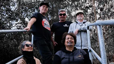 Salmonella Dub members sit on steps, leaning on metal railings