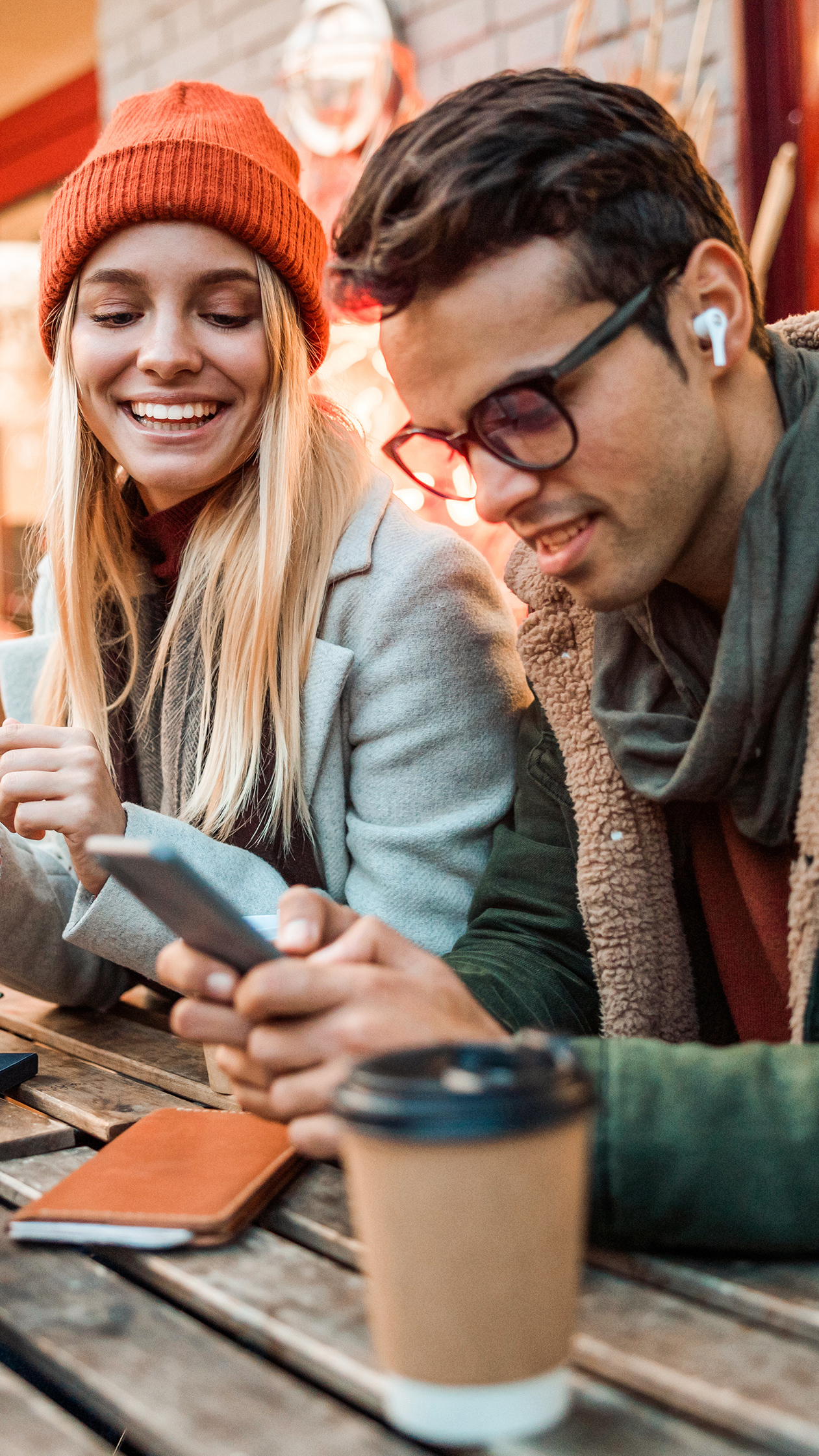 Two friends using phones at outdoor café