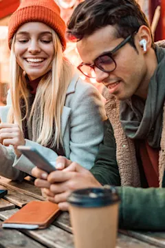 Two friends using phones at outdoor café