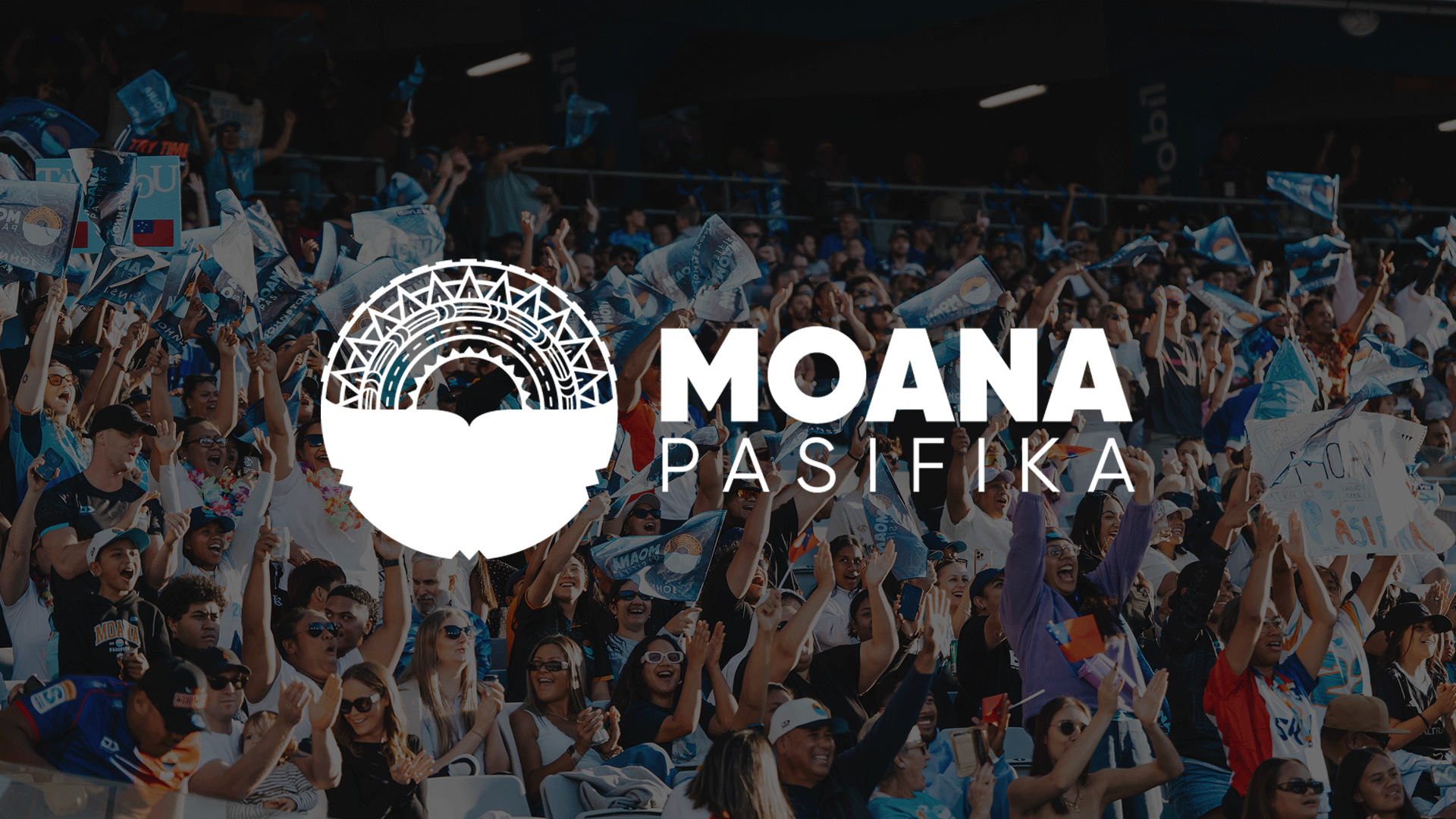A large crowd of cheering fans in a stadium, many waving blue Moana Pasifika flags, with the team's logo and name overlaid on the image.