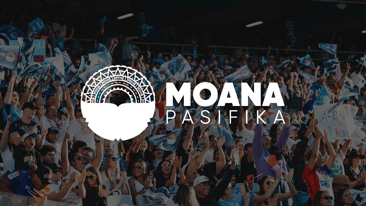 A large crowd of cheering fans in a stadium, many waving blue Moana Pasifika flags, with the team's logo and name overlaid on the image.