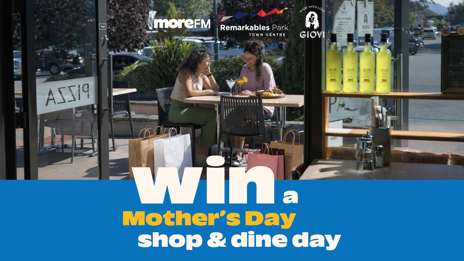 Two women happily dine outdoors at Remarkables Park Town Centre, surrounded by shopping bags, with overlay text: "Win a Mother's Day shop & dine day."