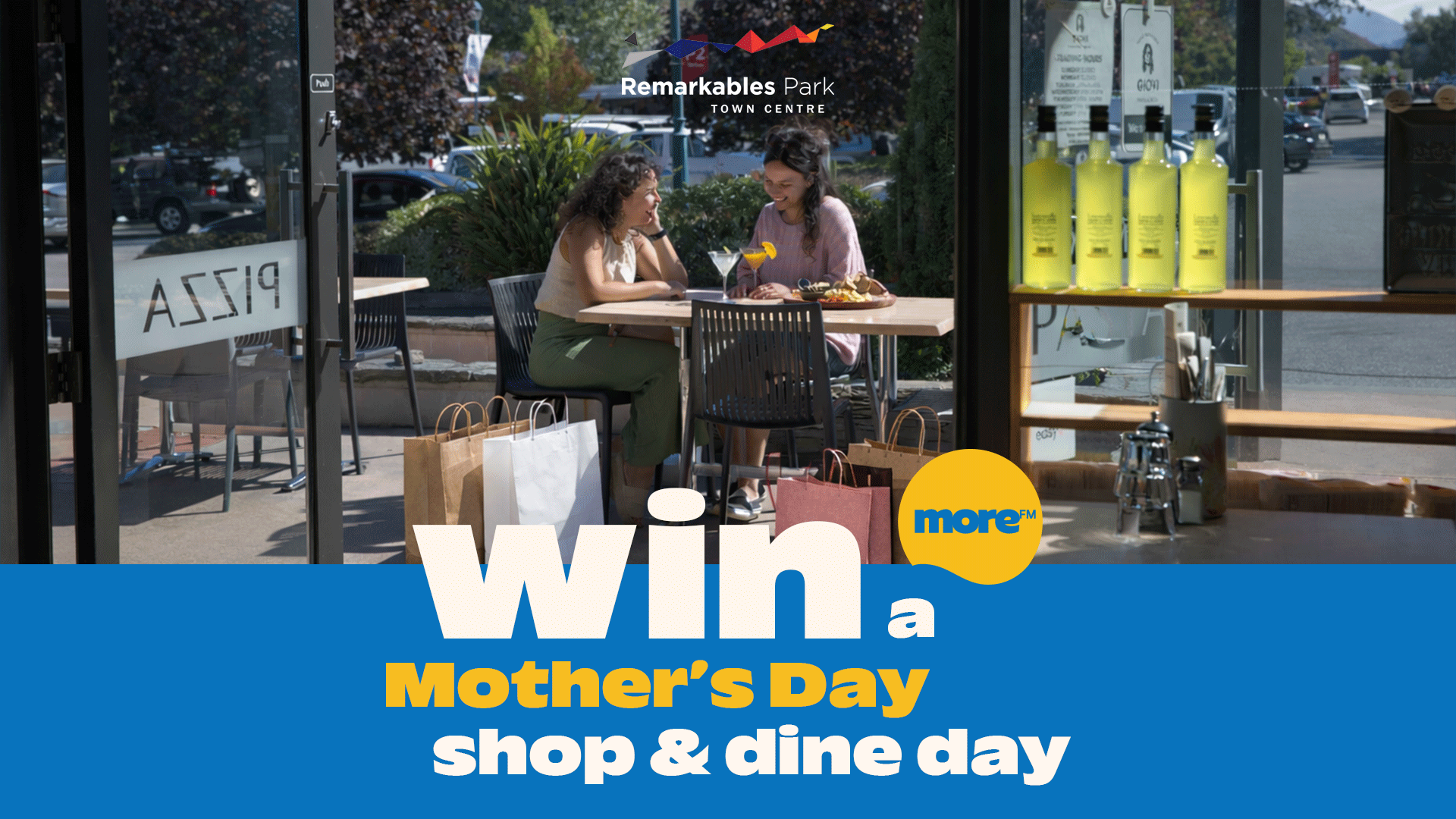 Two women happily dine outdoors at Remarkables Park Town Centre, surrounded by shopping bags, with overlay text: "Win a Mother's Day shop & dine day."
