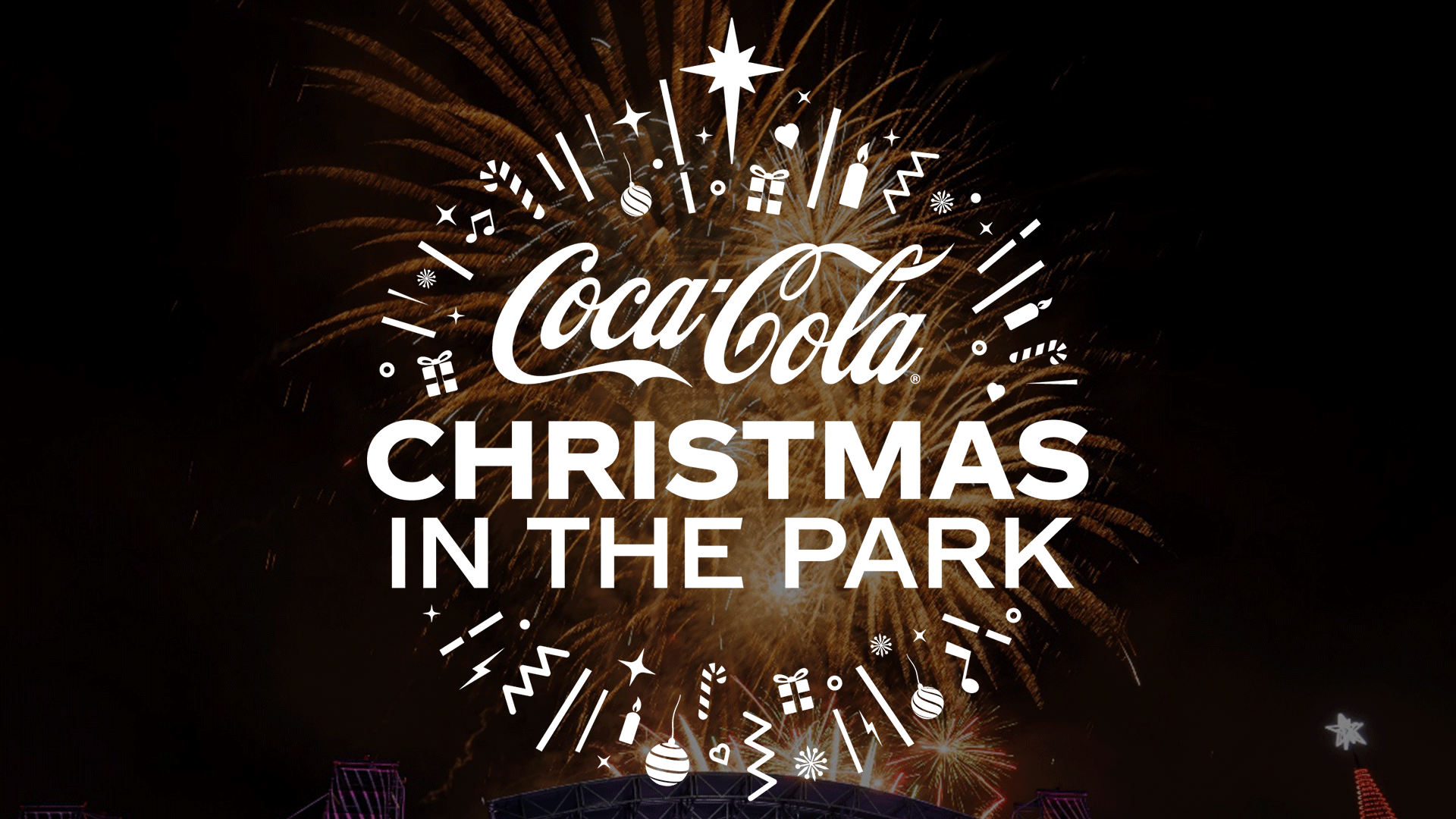 White "Coca-Cola Christmas in the Park" text, surrounded by festive icons, is set against a backdrop of golden fireworks.