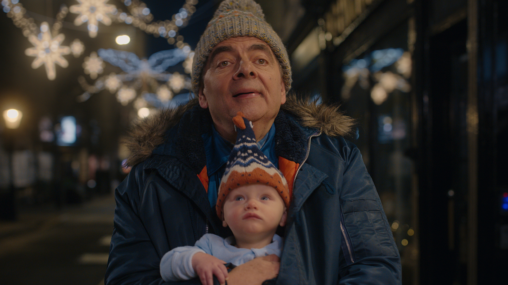 Actor Rowan Atkinson in Netflix TV series holding a baby in a Christmas setting