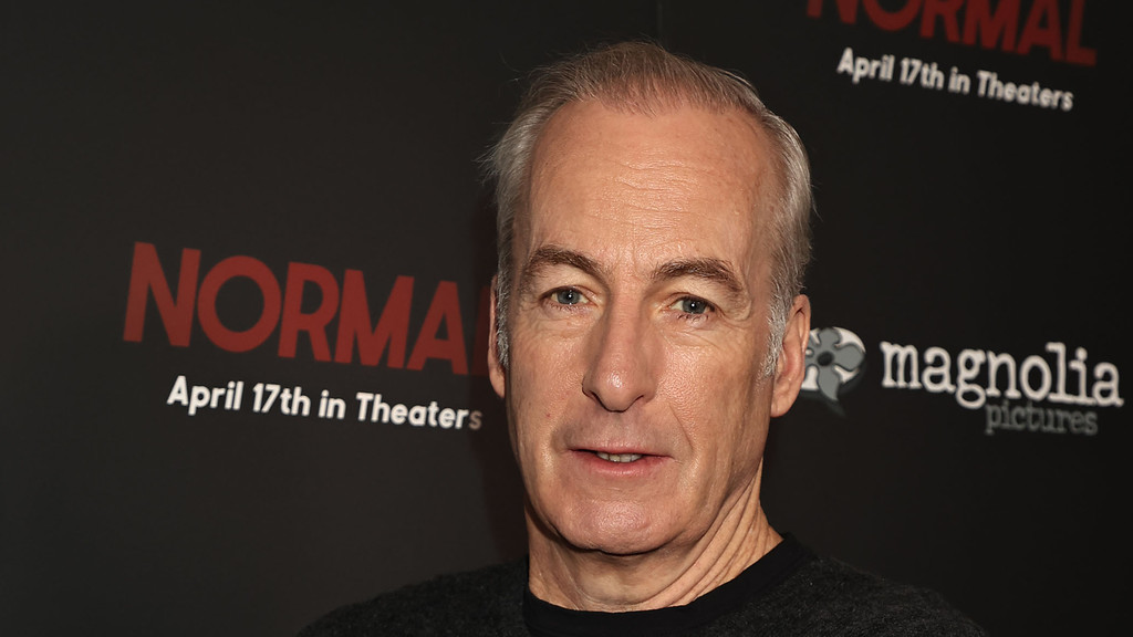 A man with grey hair and blue eyes looks directly at the camera, standing in front of a dark backdrop with the red word "NORMAL," "April 17th in Theaters," and a "magnolia pictures" logo.