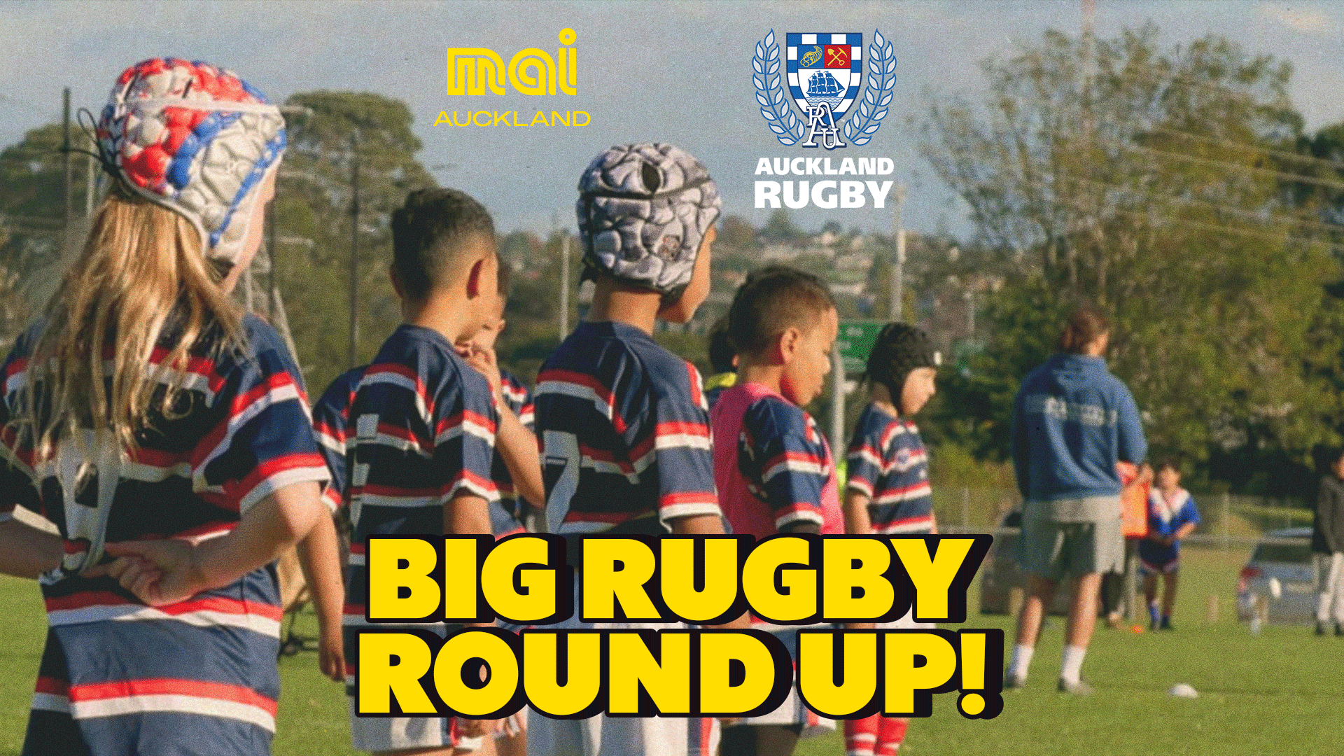 Young rugby players, some in headgear, stand on a grassy field with adults in the background, featuring "mai AUCKLAND" and "AUCKLAND RUGBY" logos and a "BIG RUGBY ROUND UP!" text overlay.