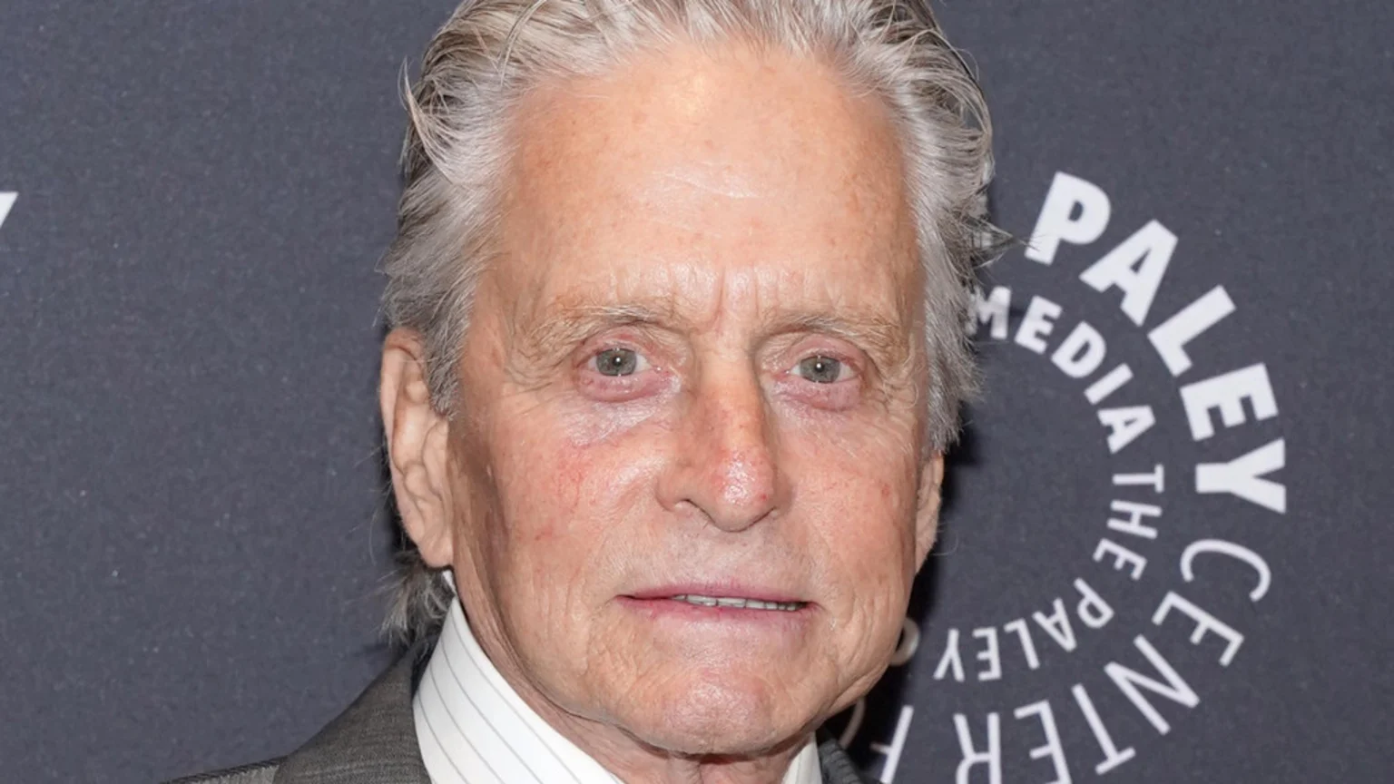 Close-up of actor Michael Douglas, an older white man with gray hair, looking forward, with a partial Paley Media Center logo visible in the dark background.