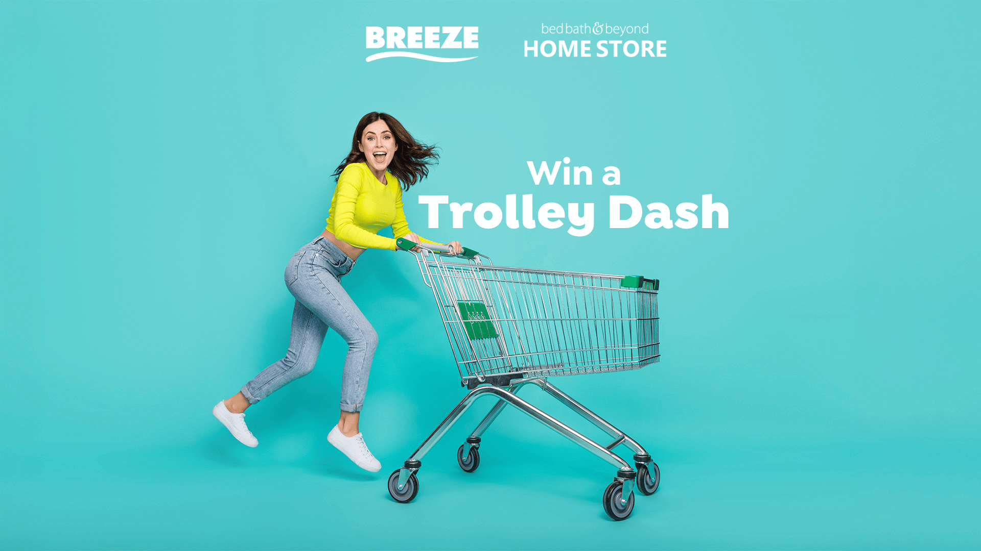A smiling woman in a neon yellow top and jeans runs excitedly while pushing an empty shopping trolley, with logos for "Breeze" and "Bed Bath & Beyond Home Store" and text "Win a Trolley Dash" above her.