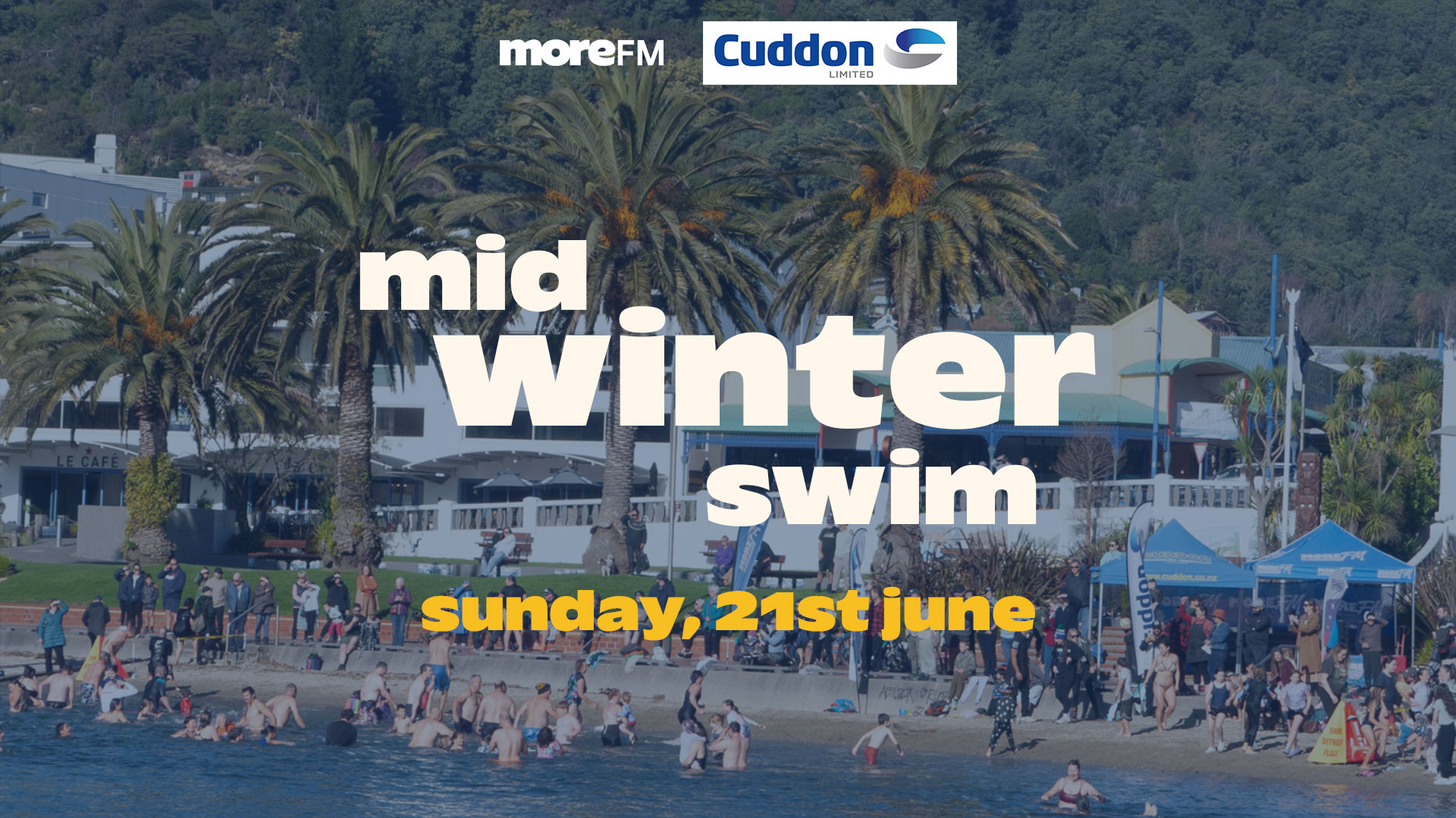 A coastal scene shows a "mid winter swim" event on Sunday, 21st June, with many people in the water and on the beach, featuring "More FM" and "Cuddon" logos.