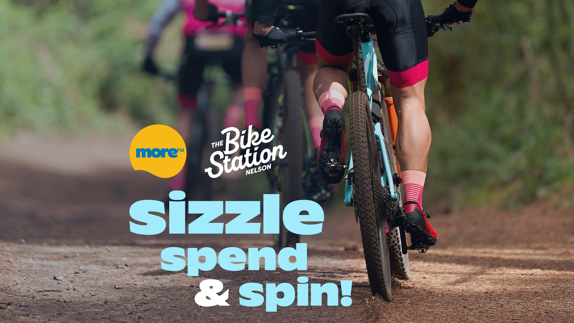 A close-up of a person on a mountain bike on a dirt trail, with two other cyclists in the background. Logos for "more™" and "The Bike Station Nelson" are overlaid, along with "sizzle spend & spin!".