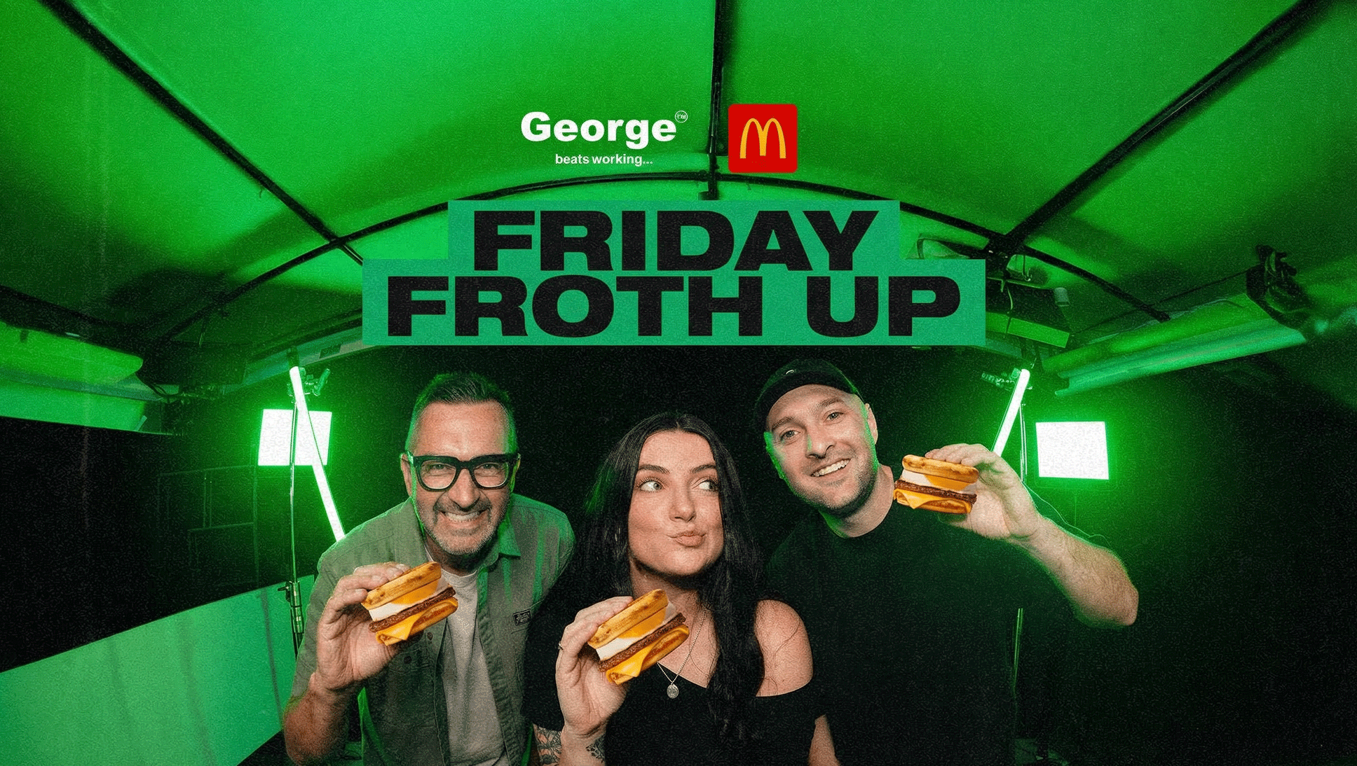Three smiling people hold McDonald's breakfast sandwiches under a banner reading "FRIDAY FROTH UP," with "George" and the McDonald's logo visible above in a green-lit setting.