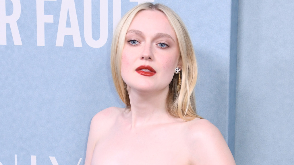 Dakota Fanning, with blonde hair, blue eyes, and red lipstick, poses in a strapless garment and an ornate earring against a light blue background with white text.