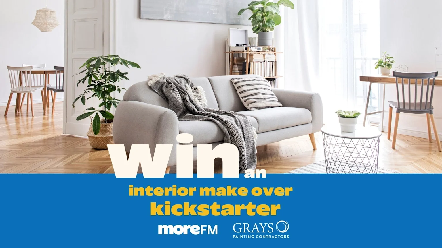 A bright, modern living room with a grey sofa, plants, and hardwood floors, featuring a blue banner overlay with "WIN an interior make over kickstarter" and sponsor logos.
