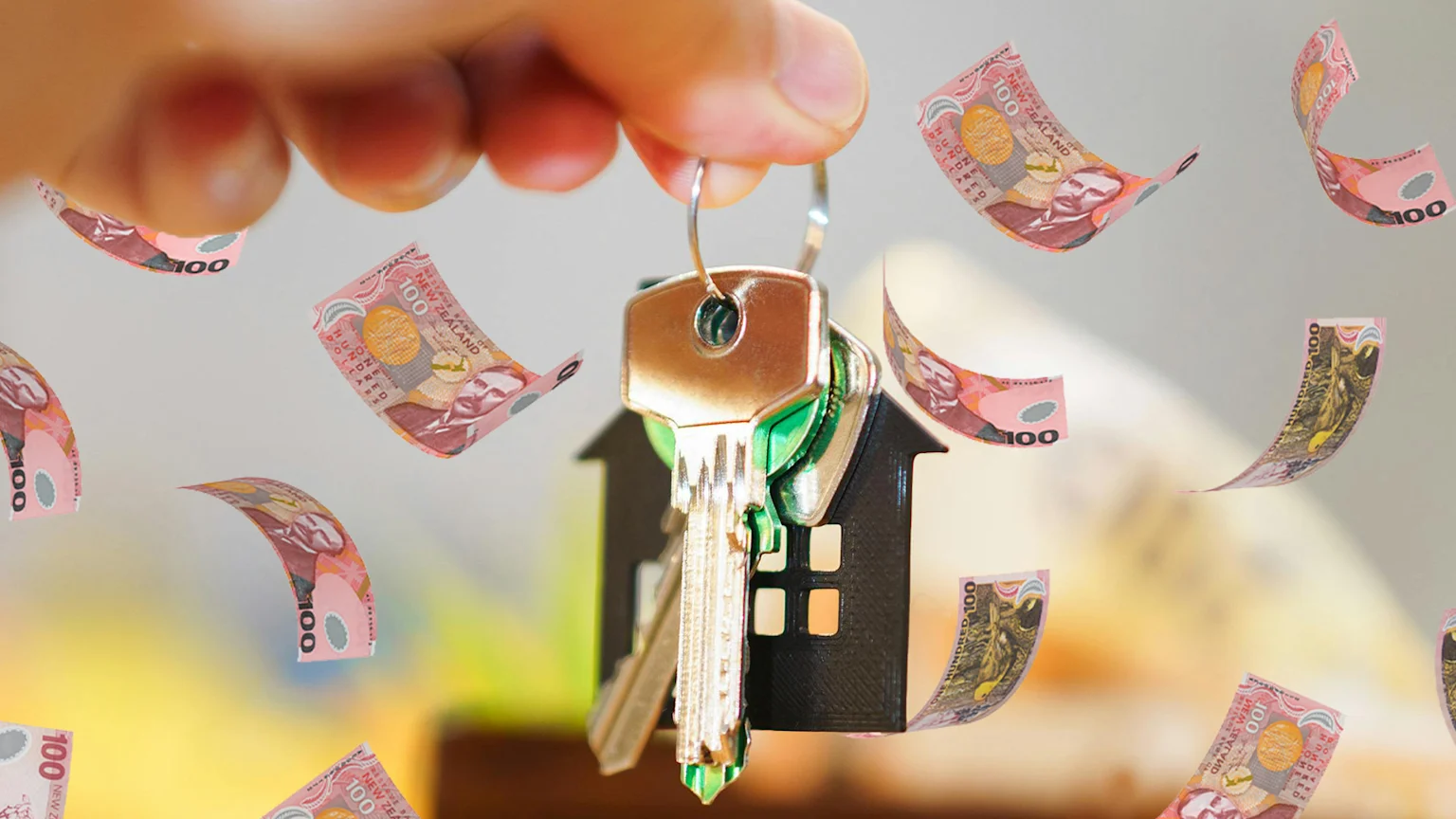 A person's hand holds a set of keys with a house keychain, while numerous pink New Zealand 100-dollar notes float around them.